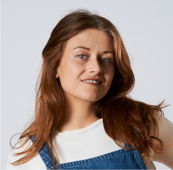 Portrait of a woman with brown hair on a flat gray background.